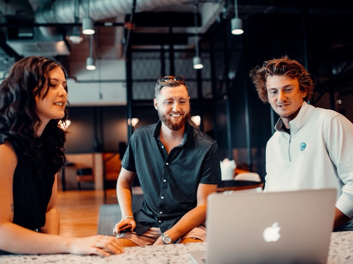 Three young people working together around a laptop
